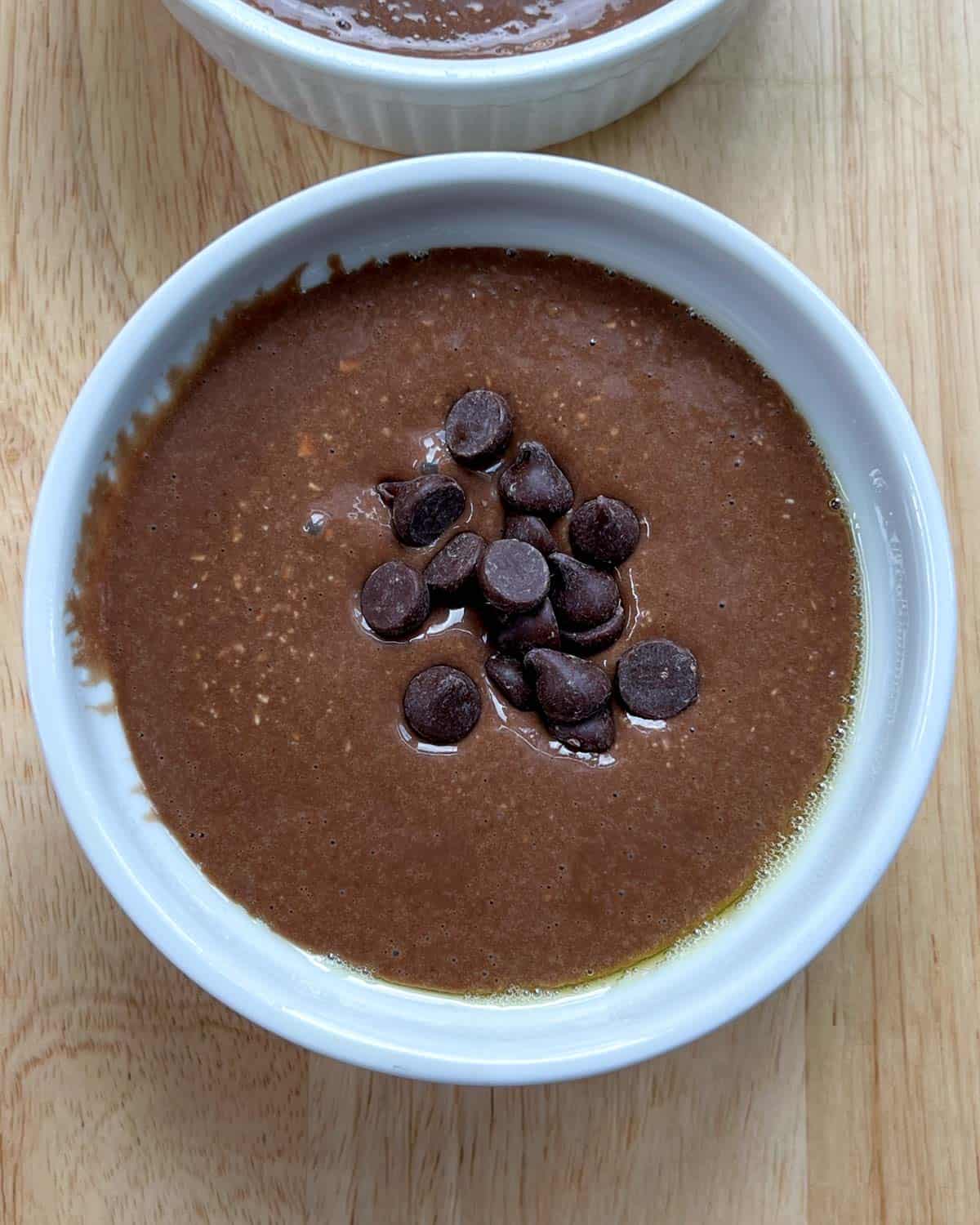 chocolate batter added into a ramekin and topped with a small amount of chocolate chips.