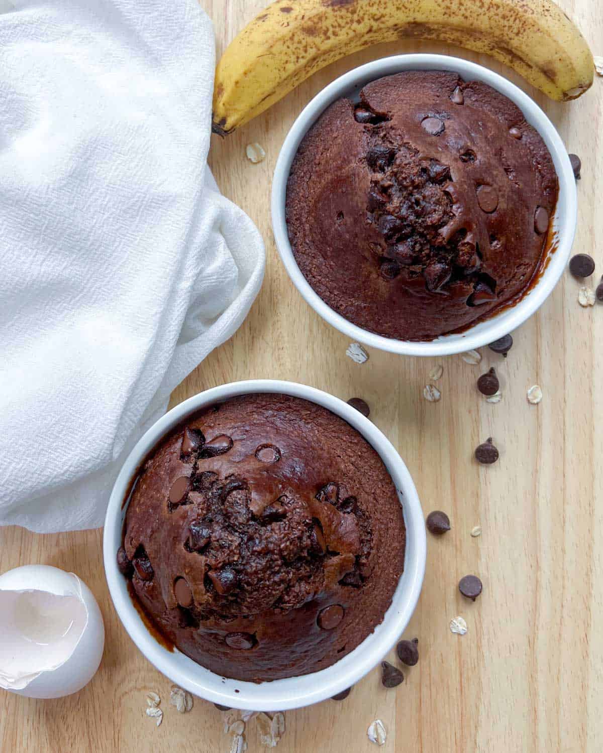 two baked oats in a ramekin with chocolate chips next to them.