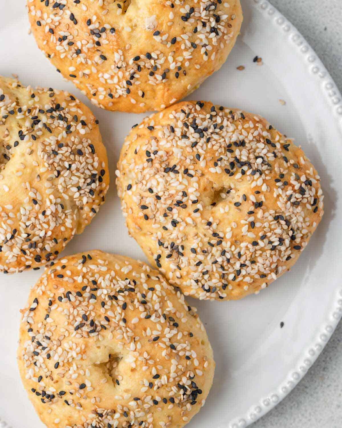 4 baked bagels on a plate.