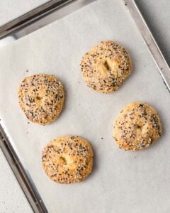 4 baked bagels on a sheet pan.