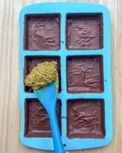 Adding the kataifi filling to the chocolate mold.