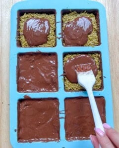 adding melted chocolate over the pistachio filling in the mold.