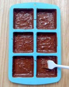 spreading melted chocolate in mold.