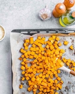 Roasted cubed butternut squash on a sheet pan.