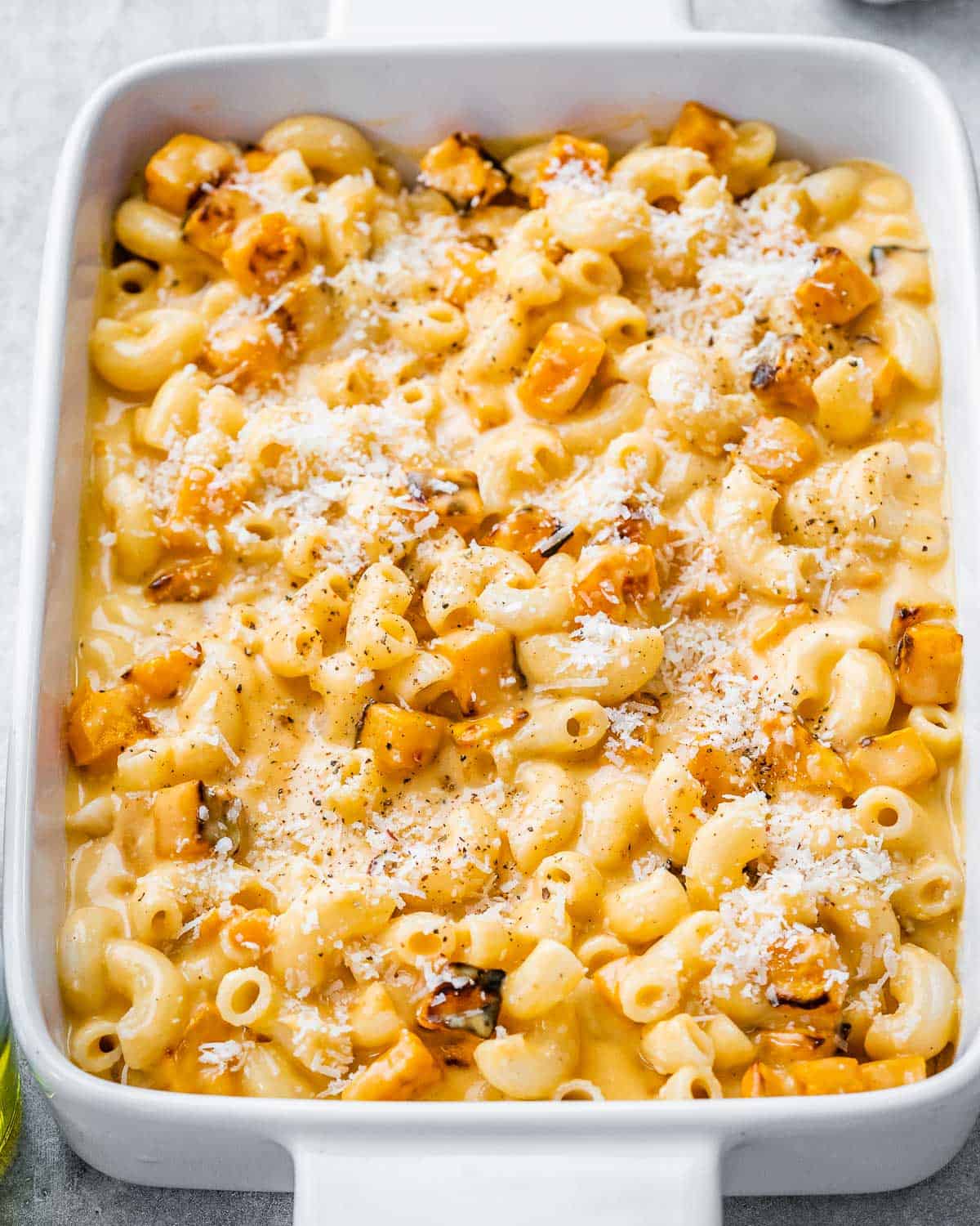 a white dish with mac and cheese made with cheese and added butternut squash.