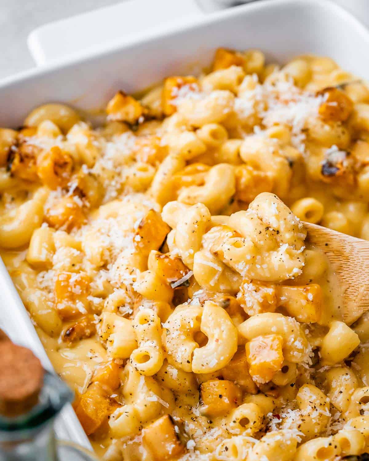 Using a wooden spoon to serve macaroni and cheese with butternut squash.