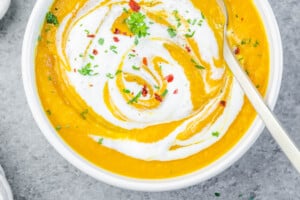 carrot ginger soup in a bowl topped with yogurt.