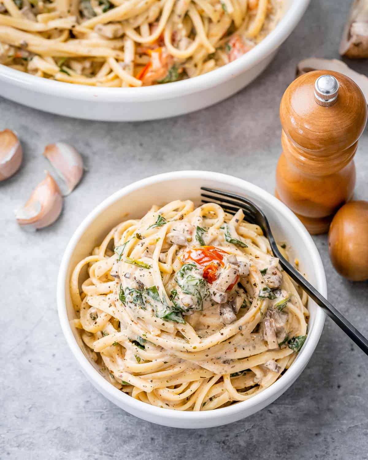 a round bowl with creamy spaghetti and a fork in the bowl.