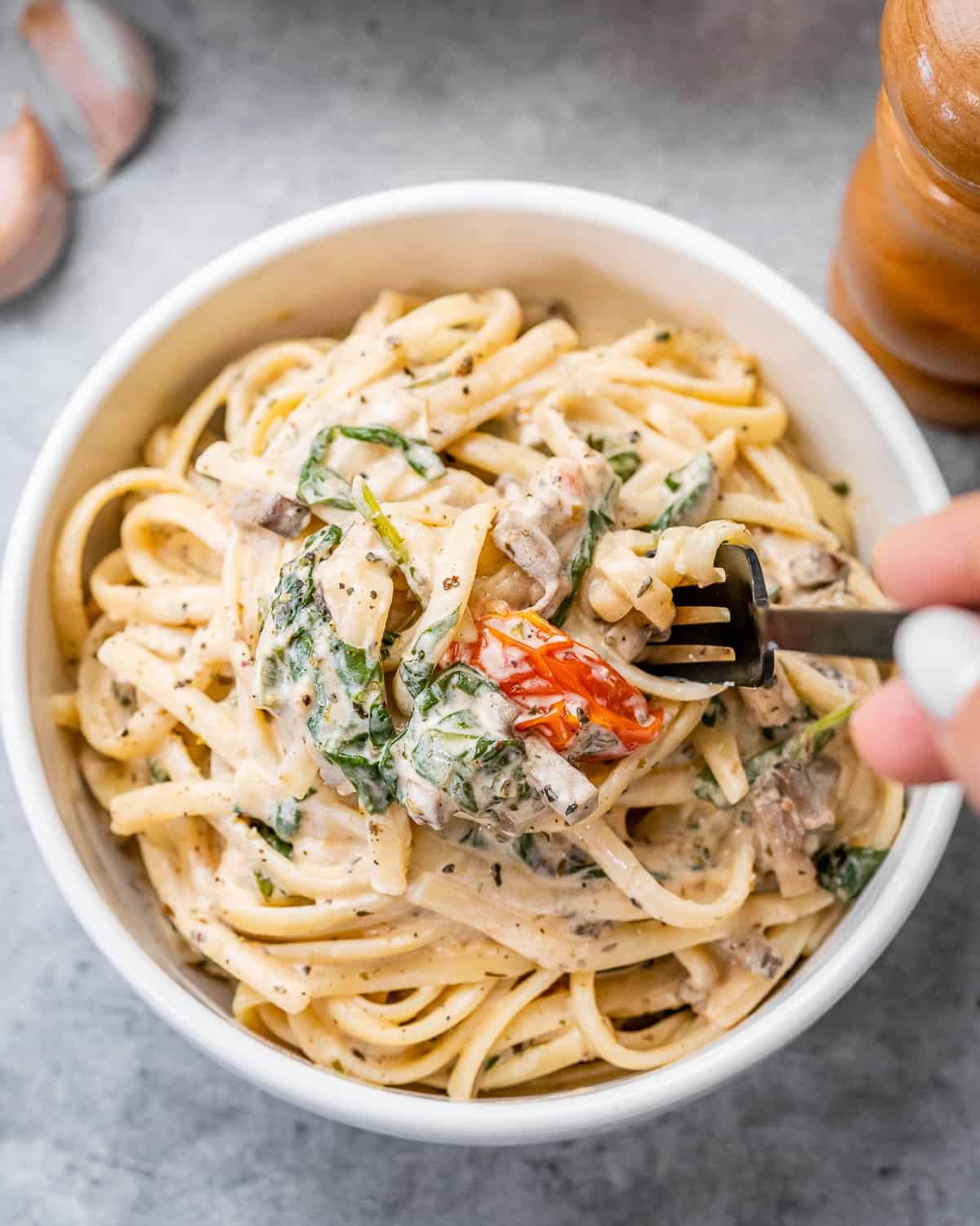 fork grabbing a bite from creamy pasta bowl.