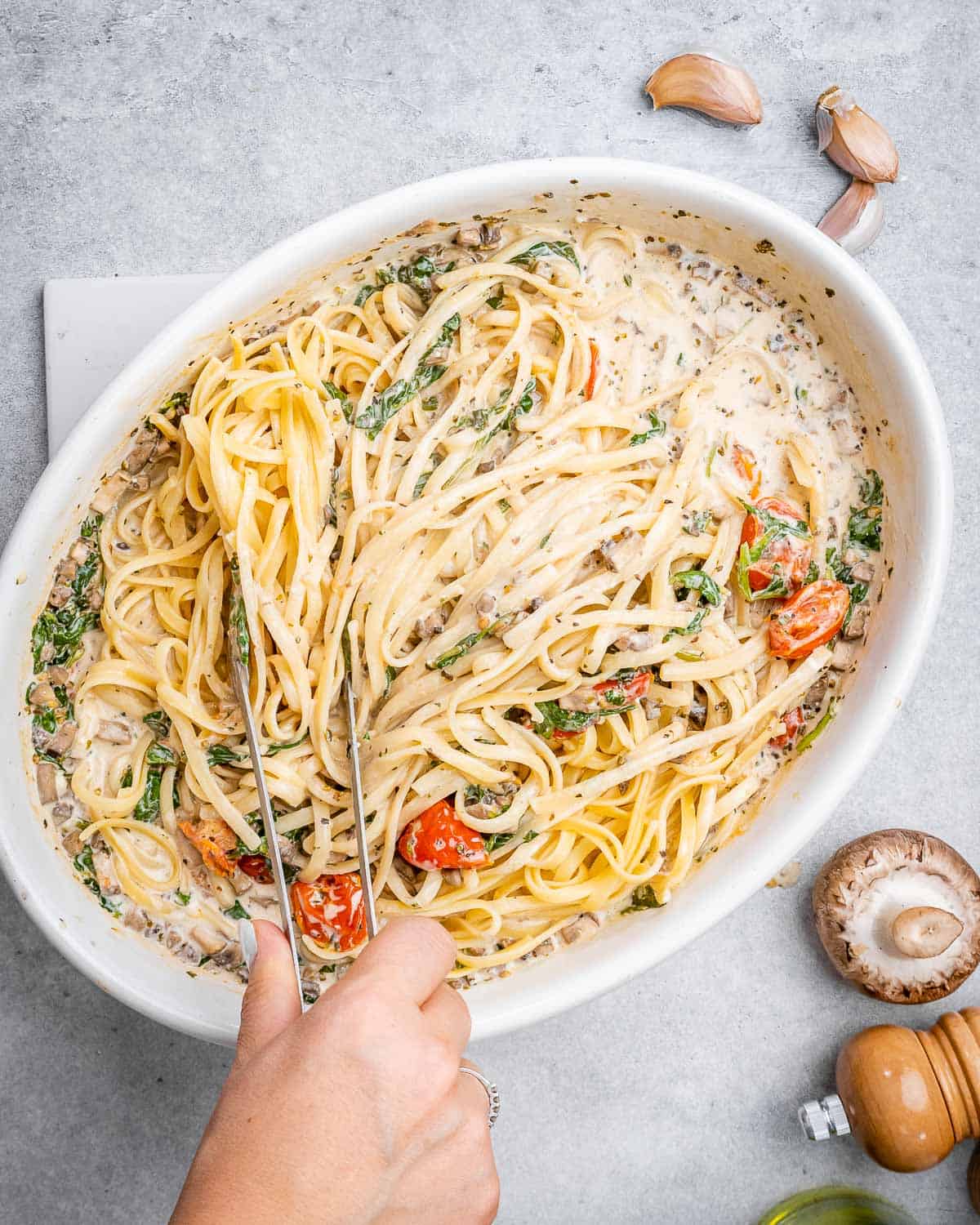 hand mixing in the pasta with the creamy veggie mix.