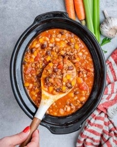 Stirring crockpot chili recipe in a slow cooker.