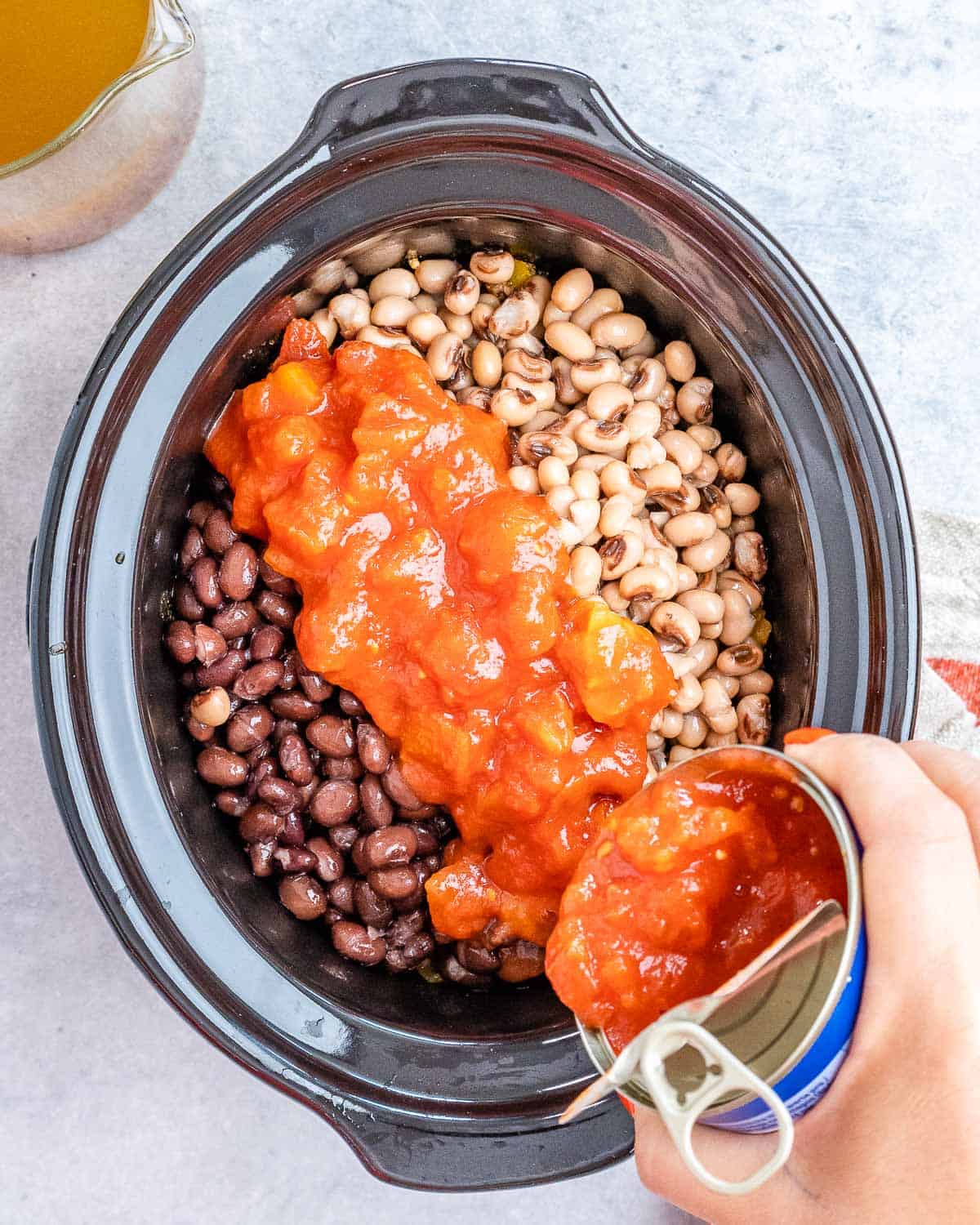 Adding beans and diced tomatoes to a crockpot.