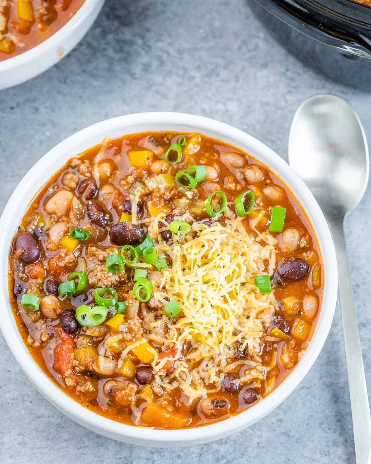 Chili with beans in a round bowl with a spoon in it.