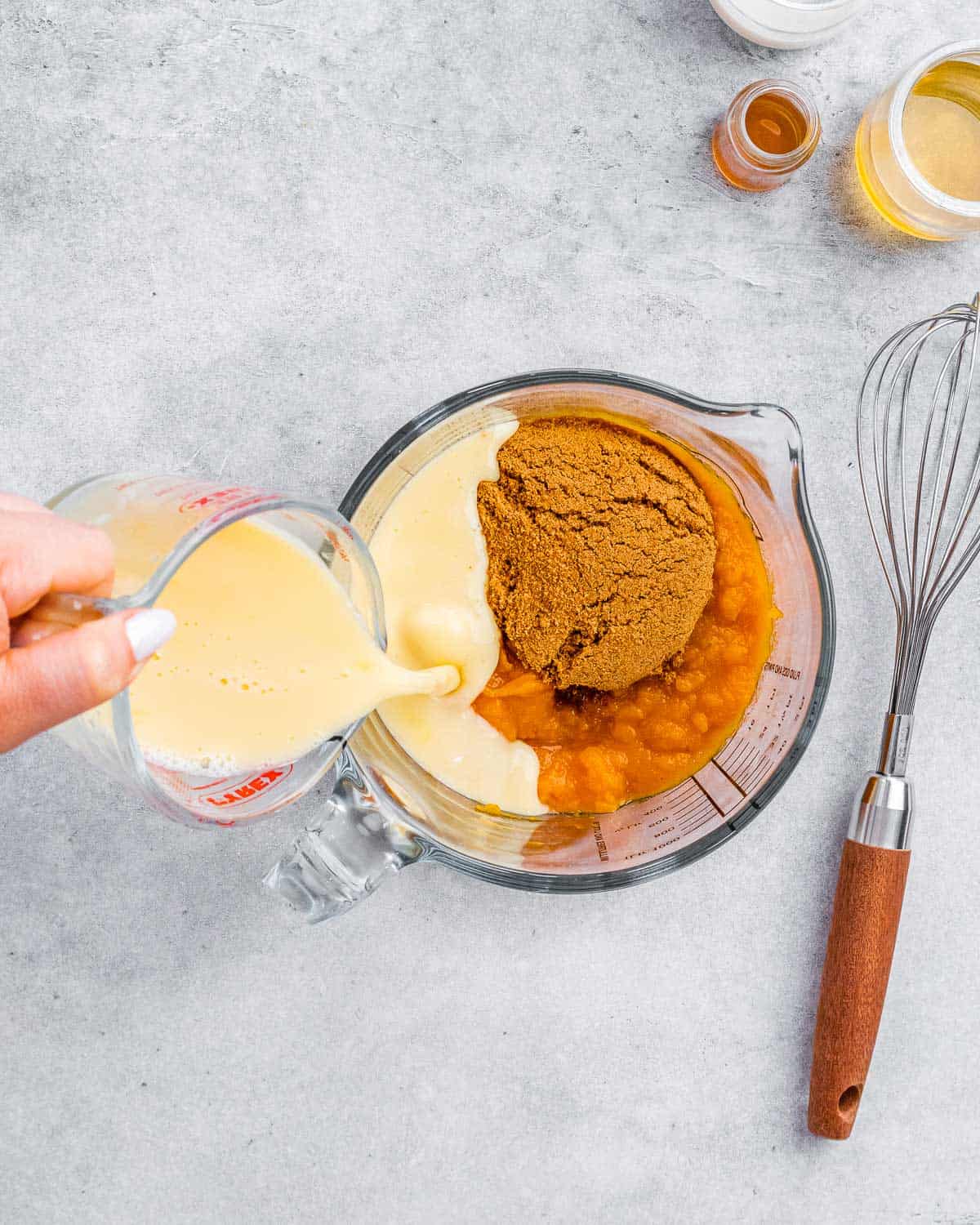 Pouring milk into a mixture of pumpkin puree, coconut sugar and spices.