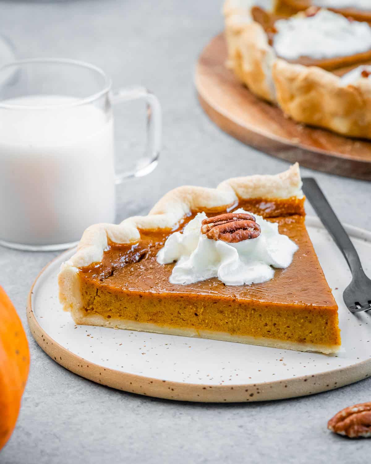 A slice of healthy pumpkin pie on a white plate with a fork.