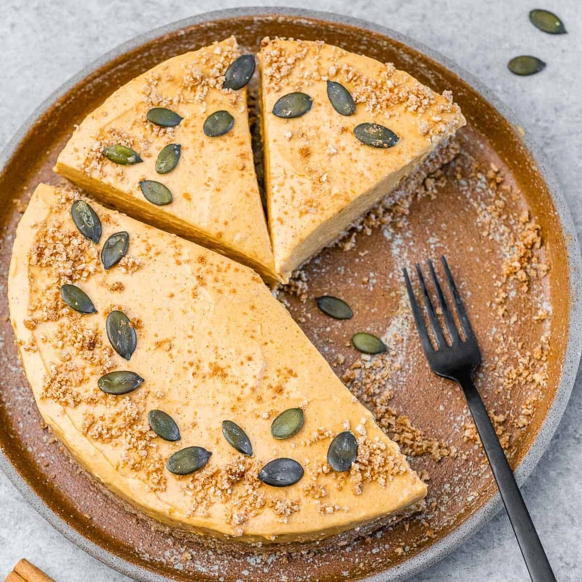 Pumpkin cheesecake with slices cut off it and fork on the plate.