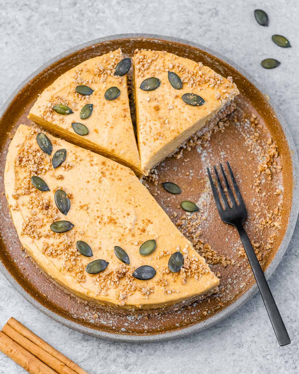 Pumpkin cheesecake with slices cut off it and fork on the plate.