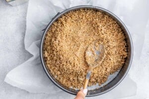 Pressing crumbled crackers into the bottom of a pan.