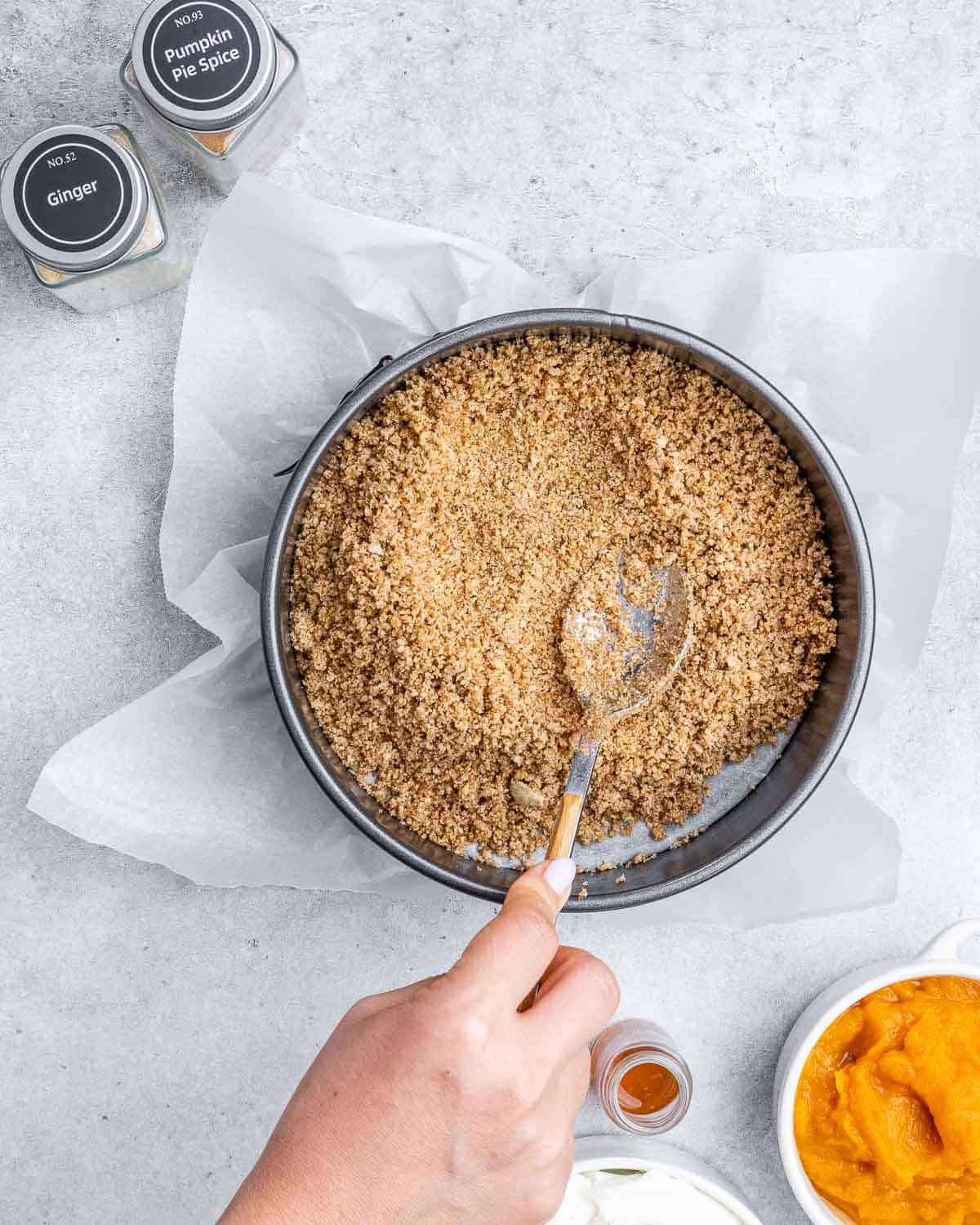 Pressing crumbled crackers into the bottom of a pan. 