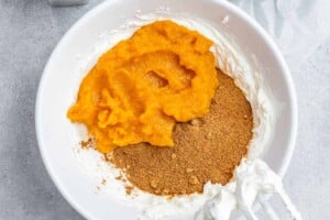 Adding sugar and pumpkin puree to whipped cream cheese.