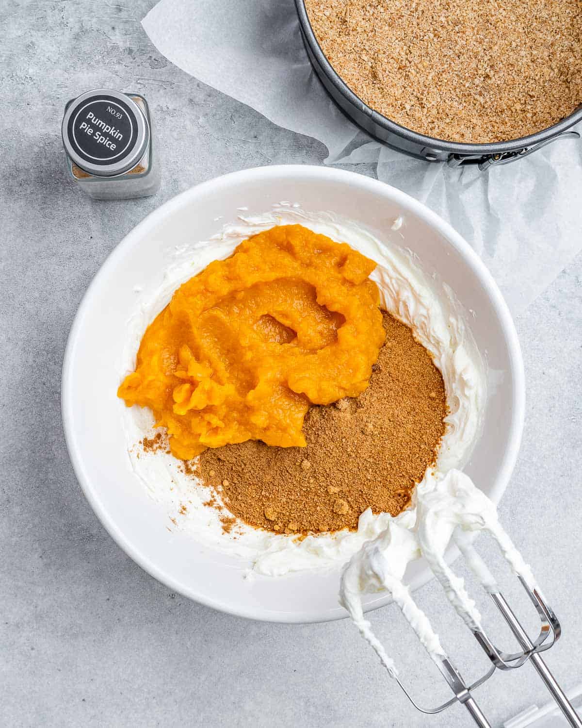 Adding sugar and pumpkin puree to whipped cream cheese.