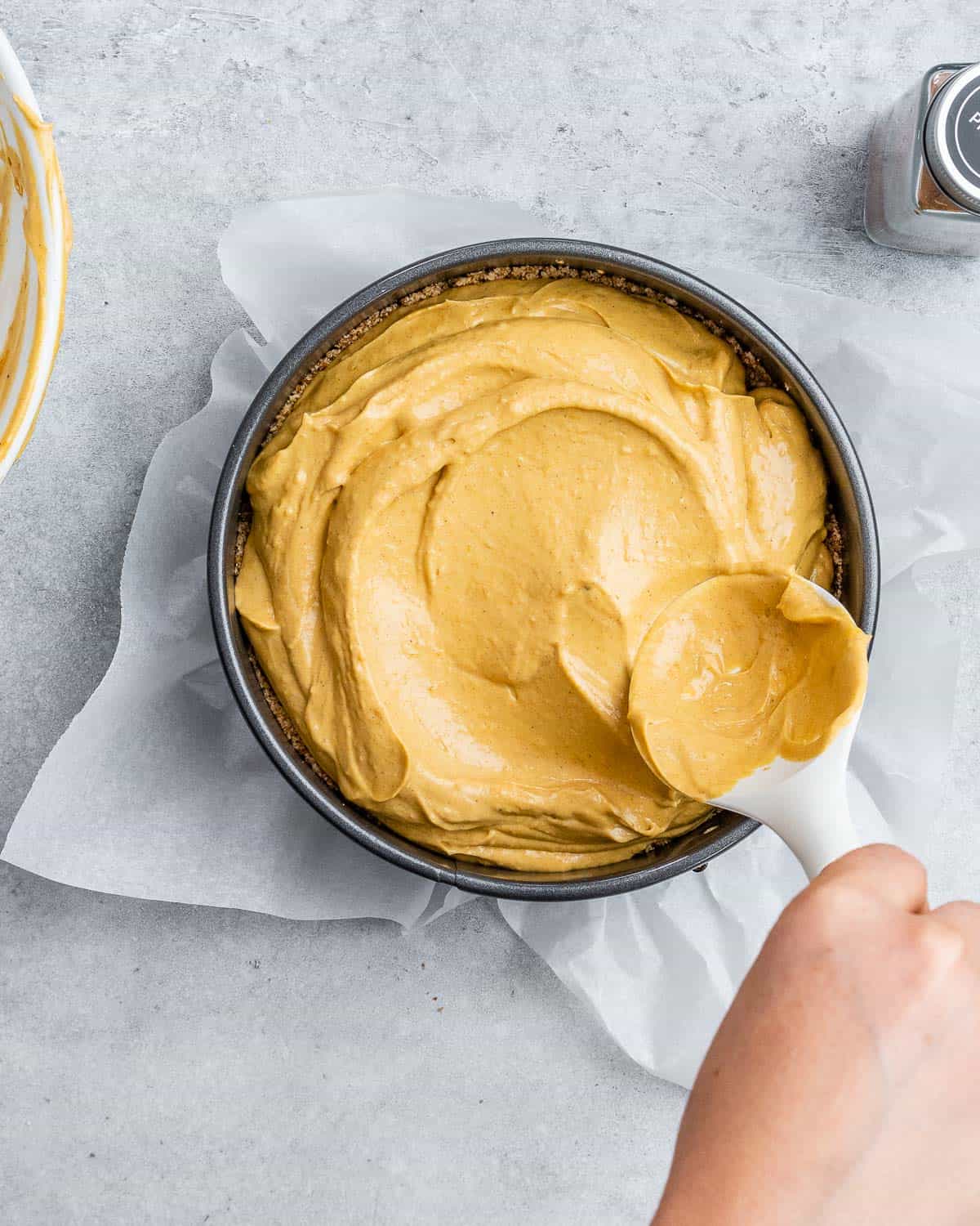 Spreading pumpkin cheesecake filling into a springform pan.