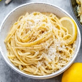 lemon linguine pasta in a white bowl topped with shaved parmesan.