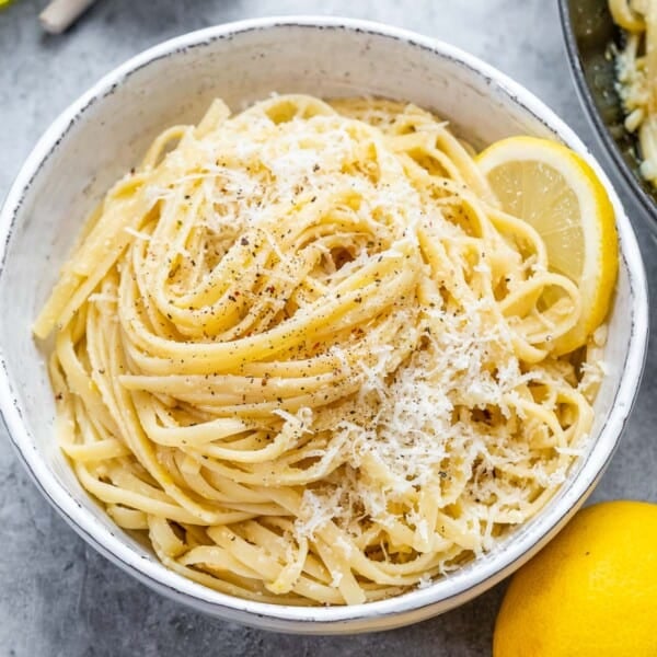 lemon linguine pasta in a white bowl topped with shaved parmesan.