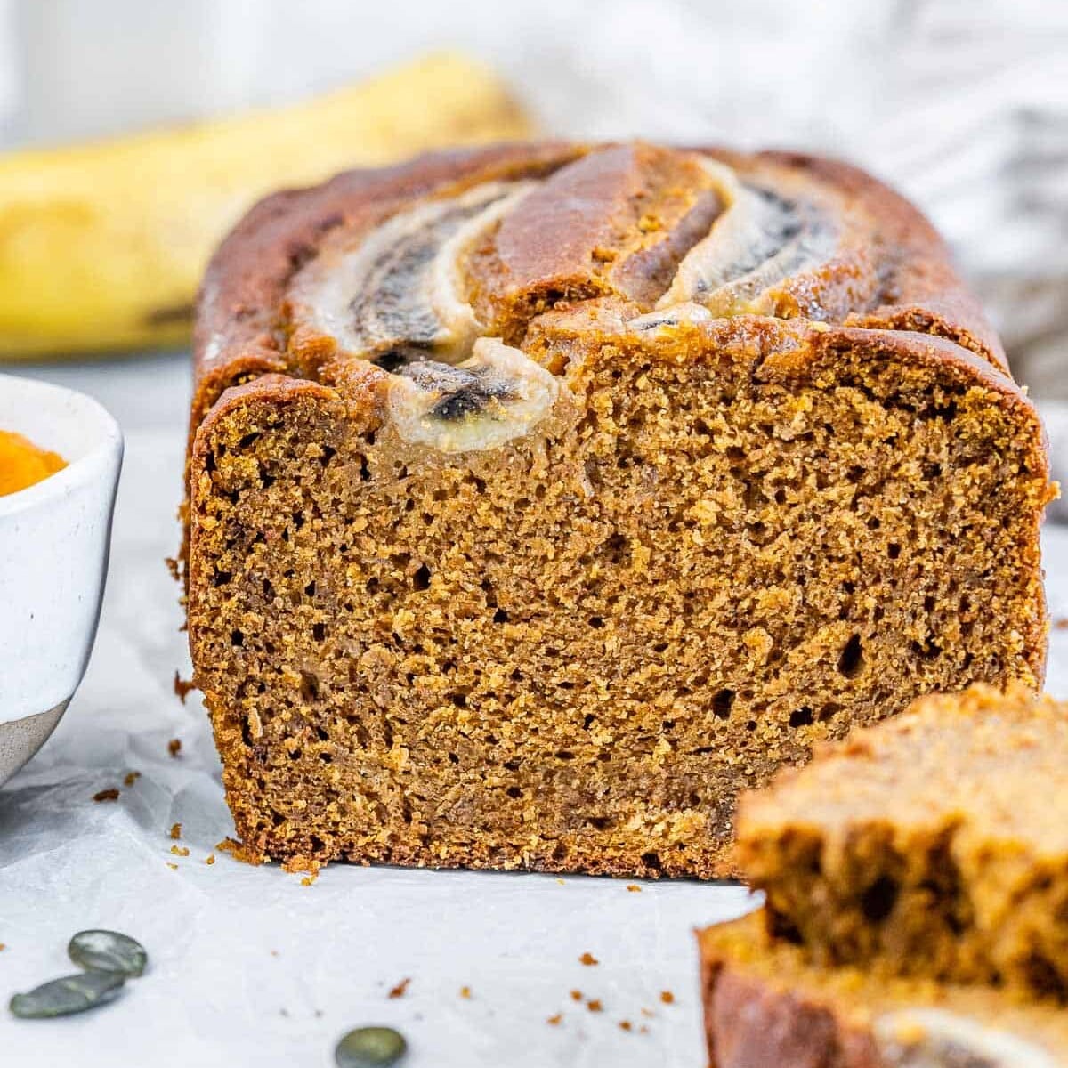 Pumpkin bread on a flat surface with two slices sliced off.