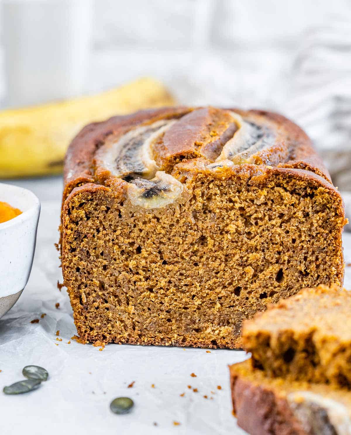 Pumpkin bread on a flat surface with two slices sliced off.