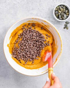 Folding chocolate chips into pumpkin cake batter.