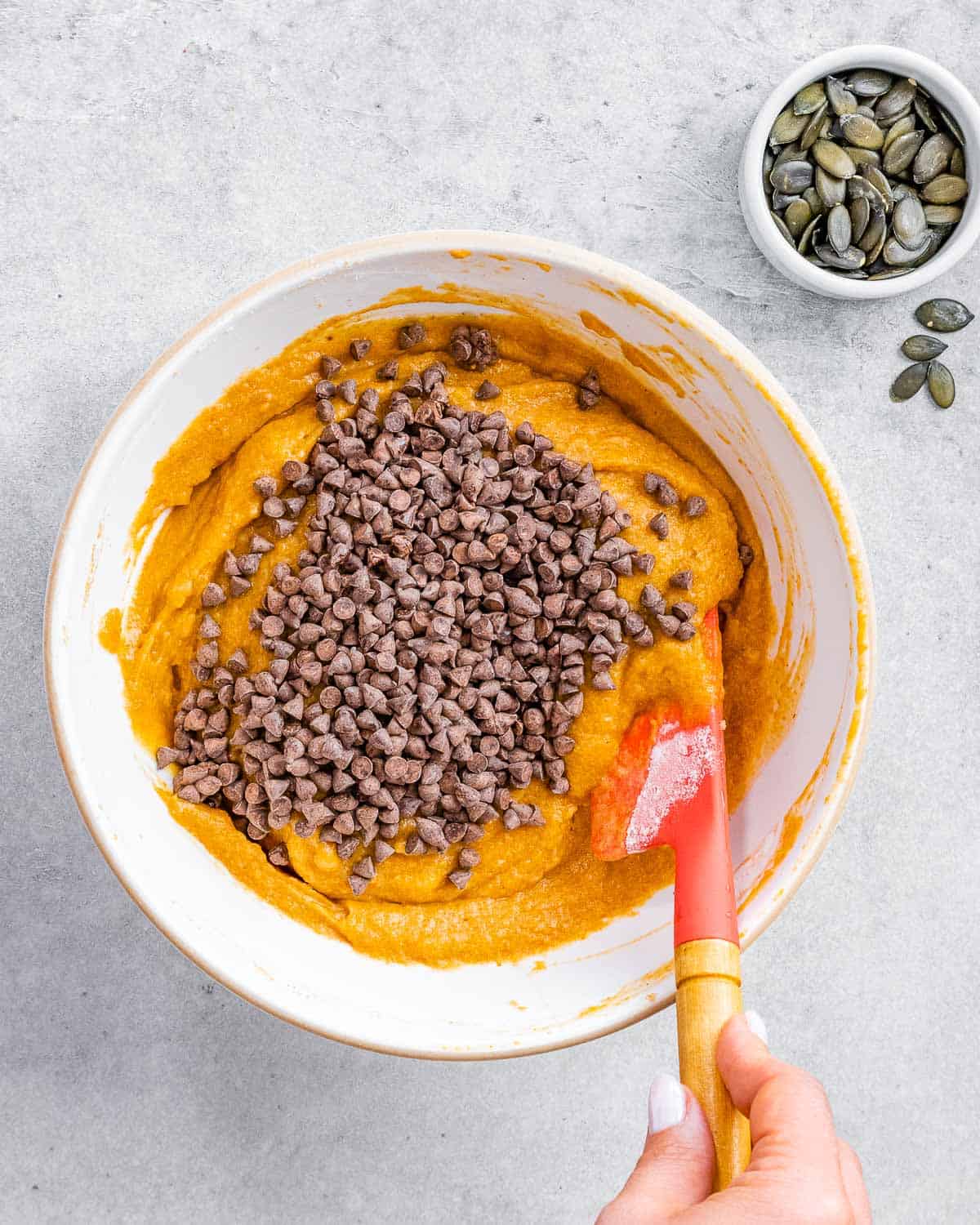 Folding chocolate chips into pumpkin cake batter.