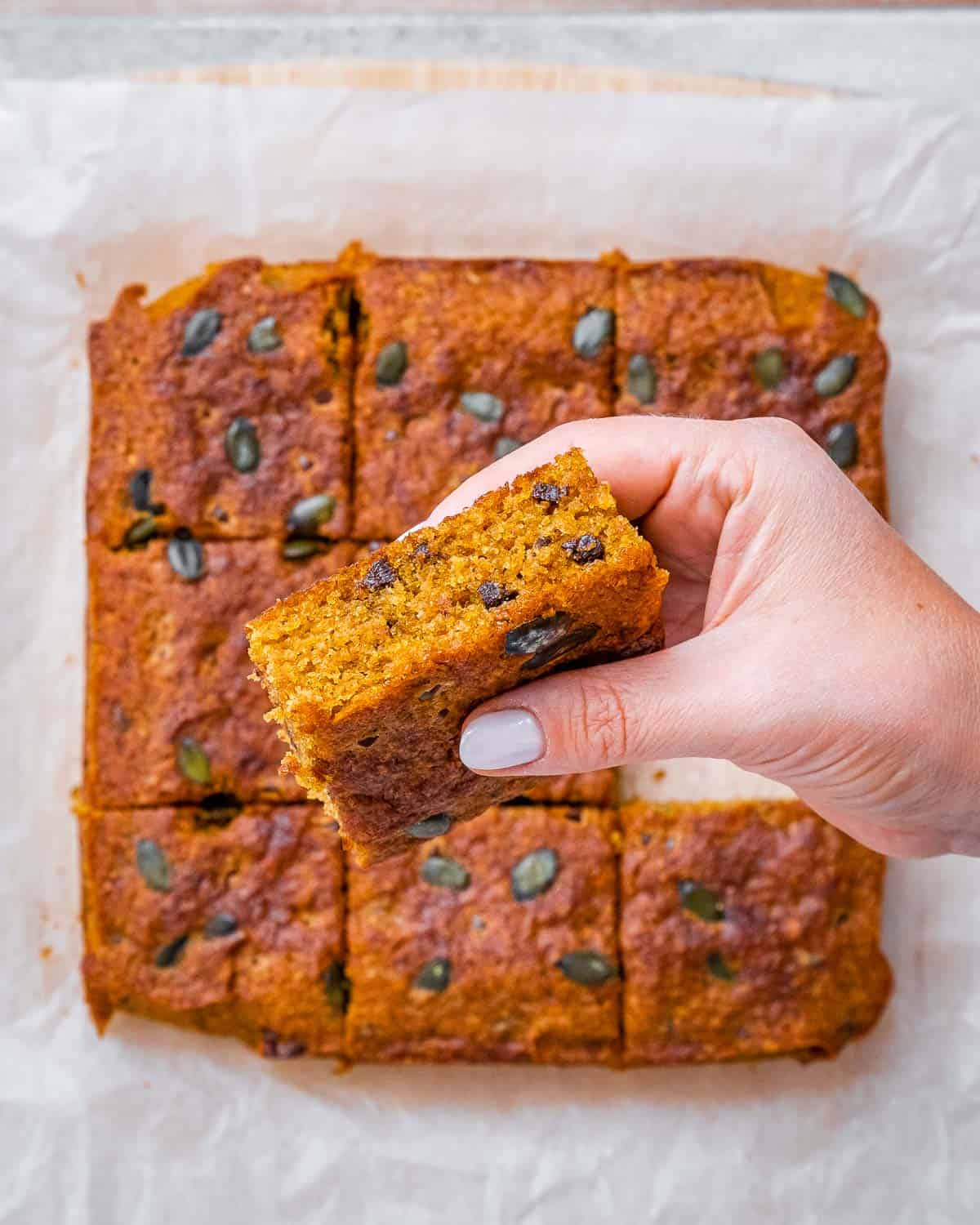 Hand holding a pumpkin bar with chocolate chips.