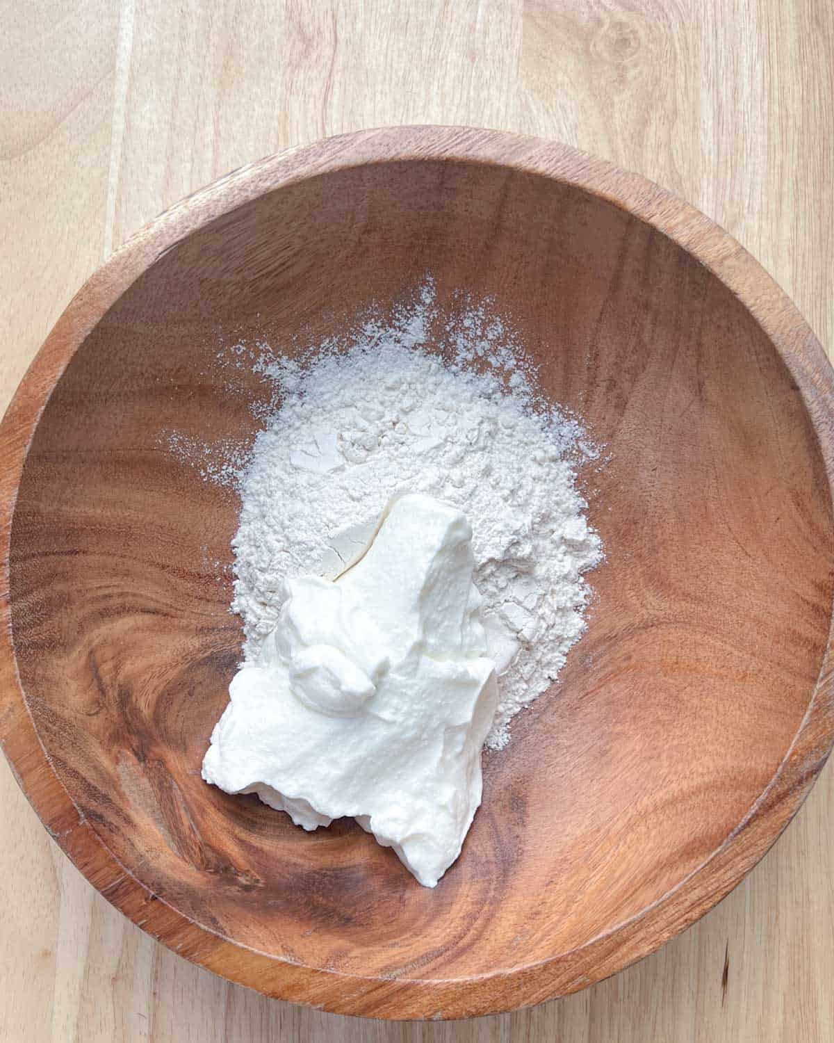 flour and yogurt added to a brown bowl.