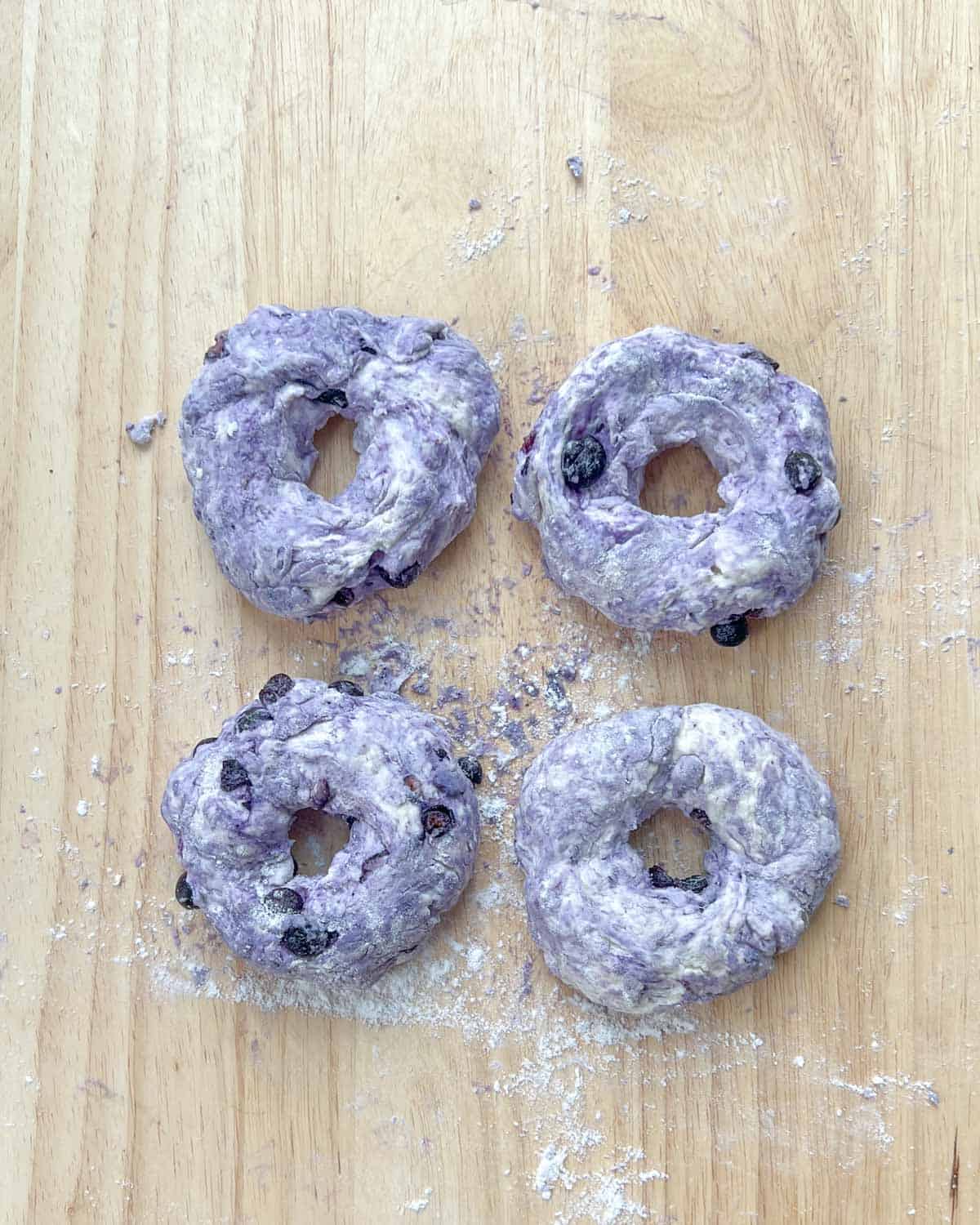 Four bagels formed with the dough on a cutting board.