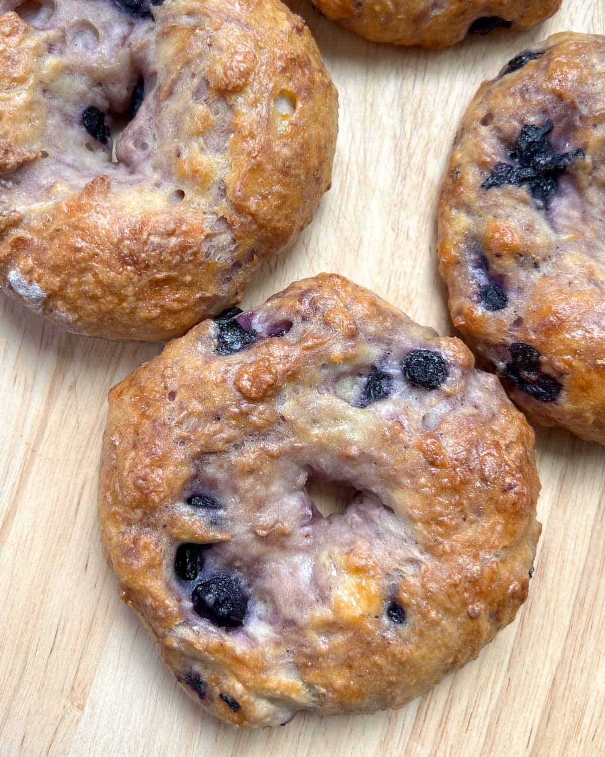 4 blueberry bagels on a flat surface.