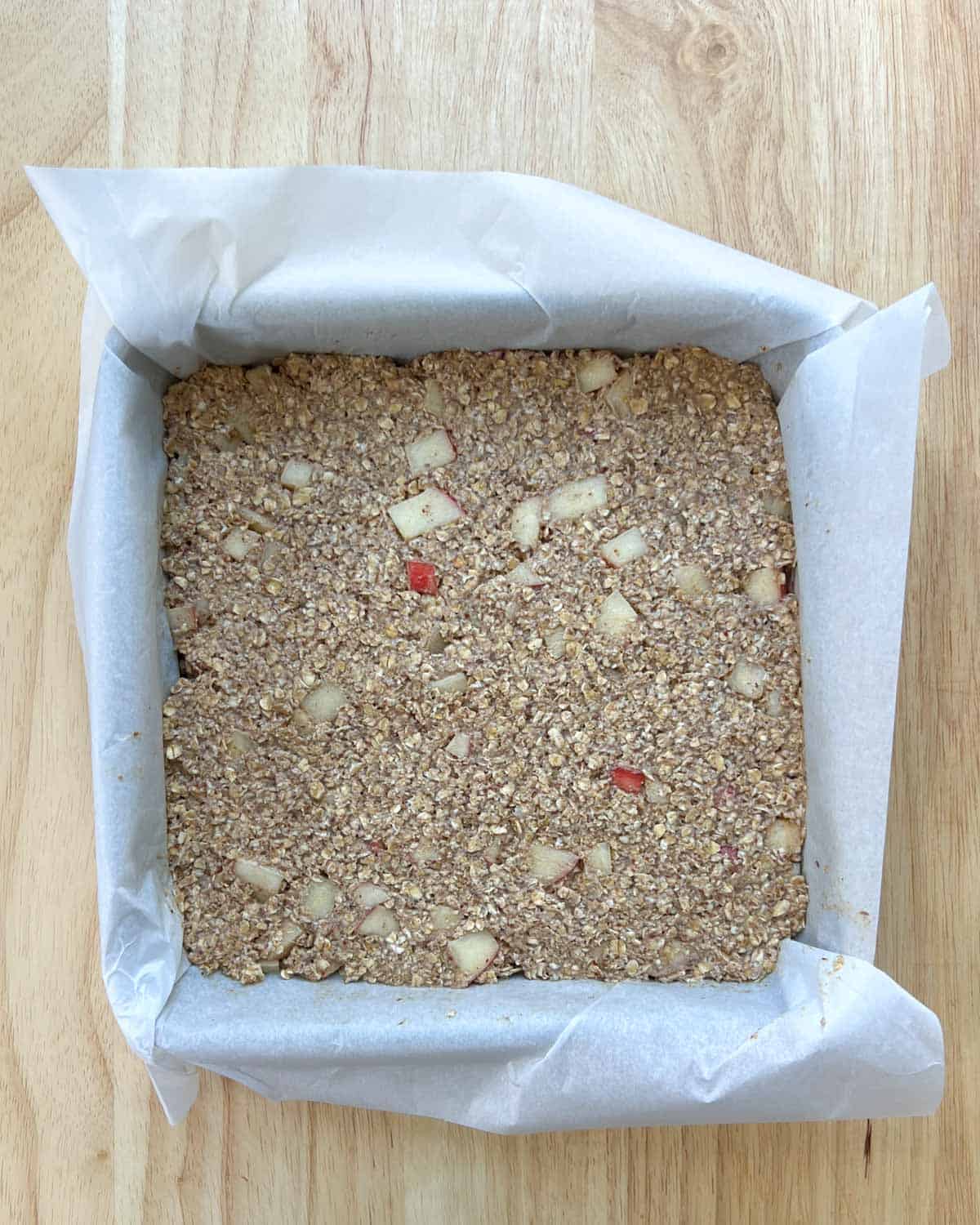 apple oatmeal batter added to a square pan before baking.