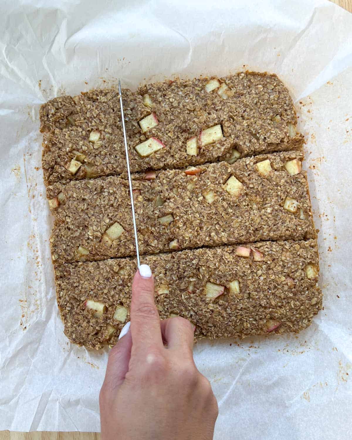 hand cutting oatmeal bars with a knife.