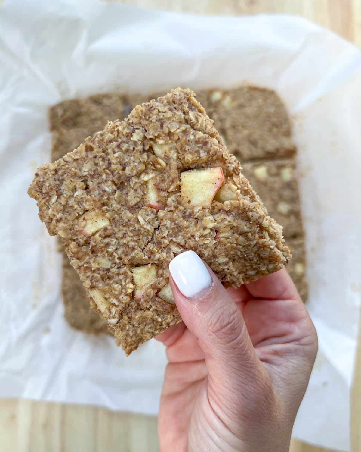 hand holding an oatmeal bar with chopped apples.