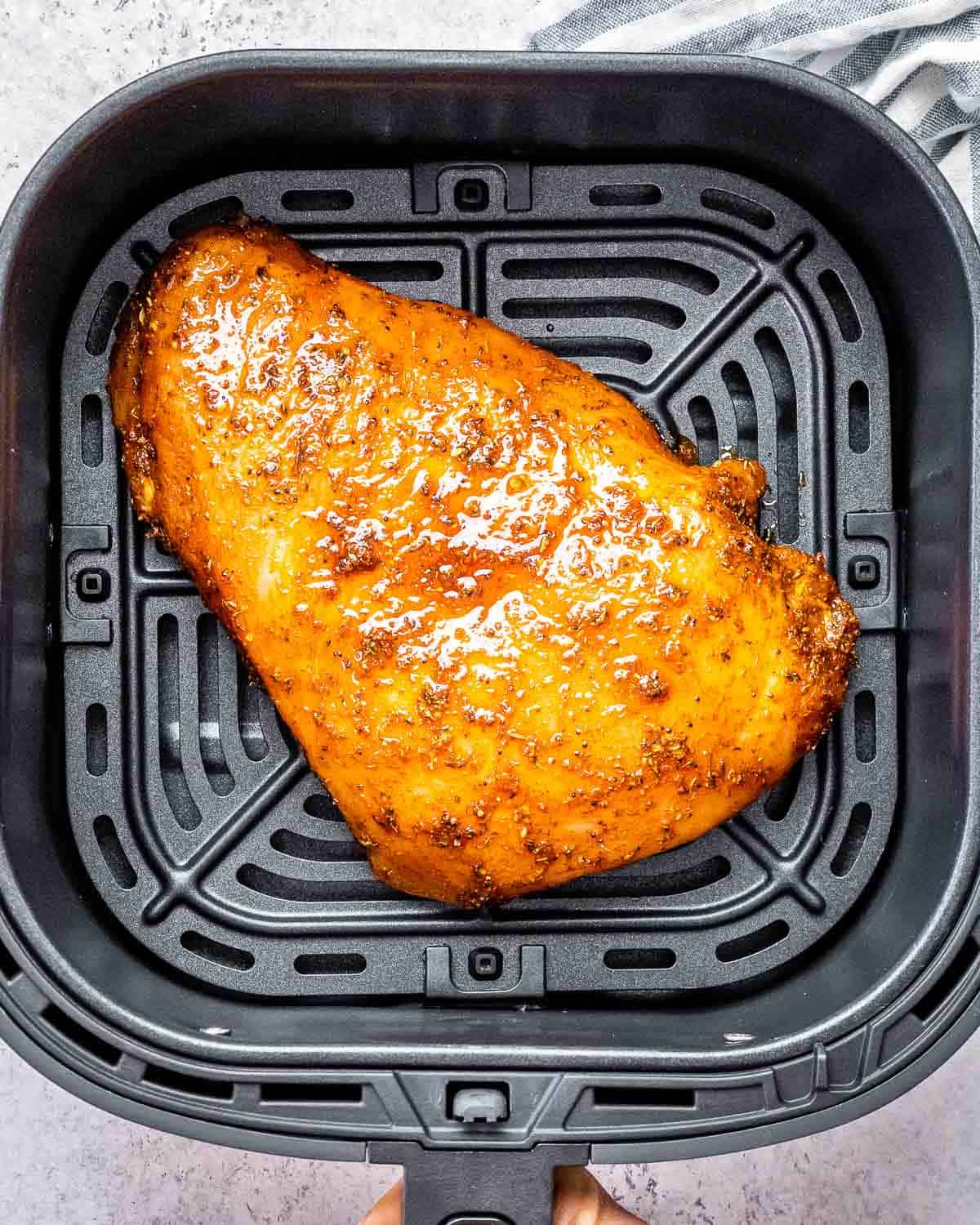 seasoned turkey breast placed in an air fryer basket.