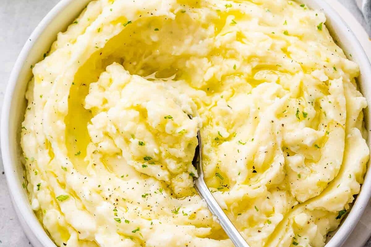 a spoon in a bowl of boursin mashed potatoes.