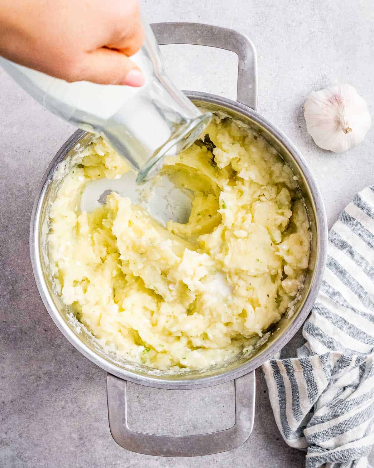 Pouring warm milk into mashed potatoes.