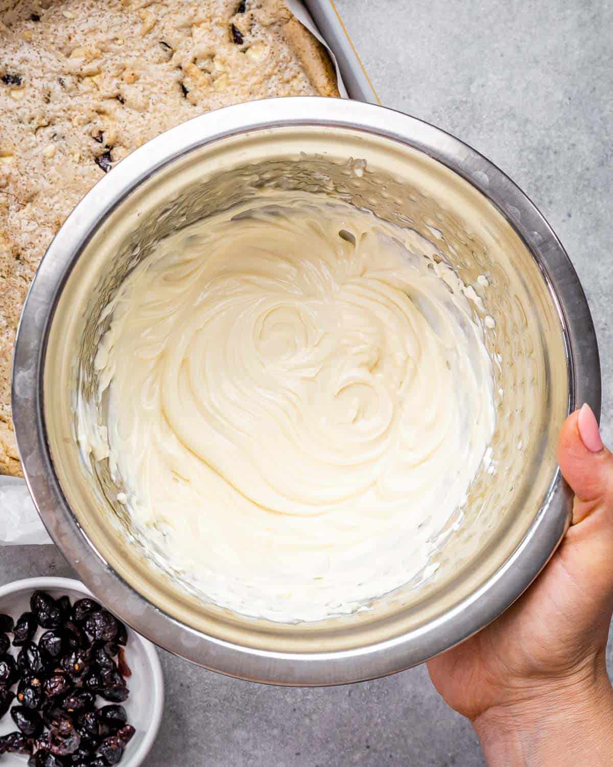 hand holding a bowl of cream cheese mixture.