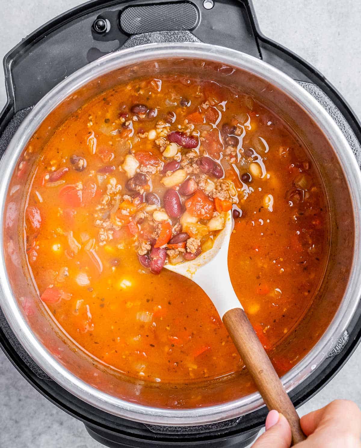 A white spatula stirring a pot of chili.