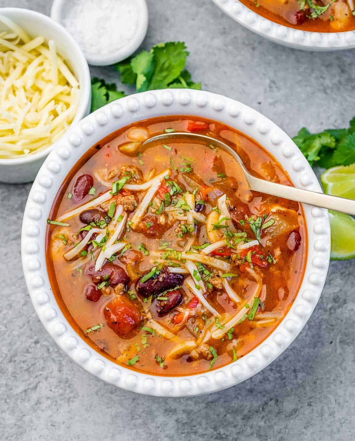 A white bowl of chili with spoon in the bowl.