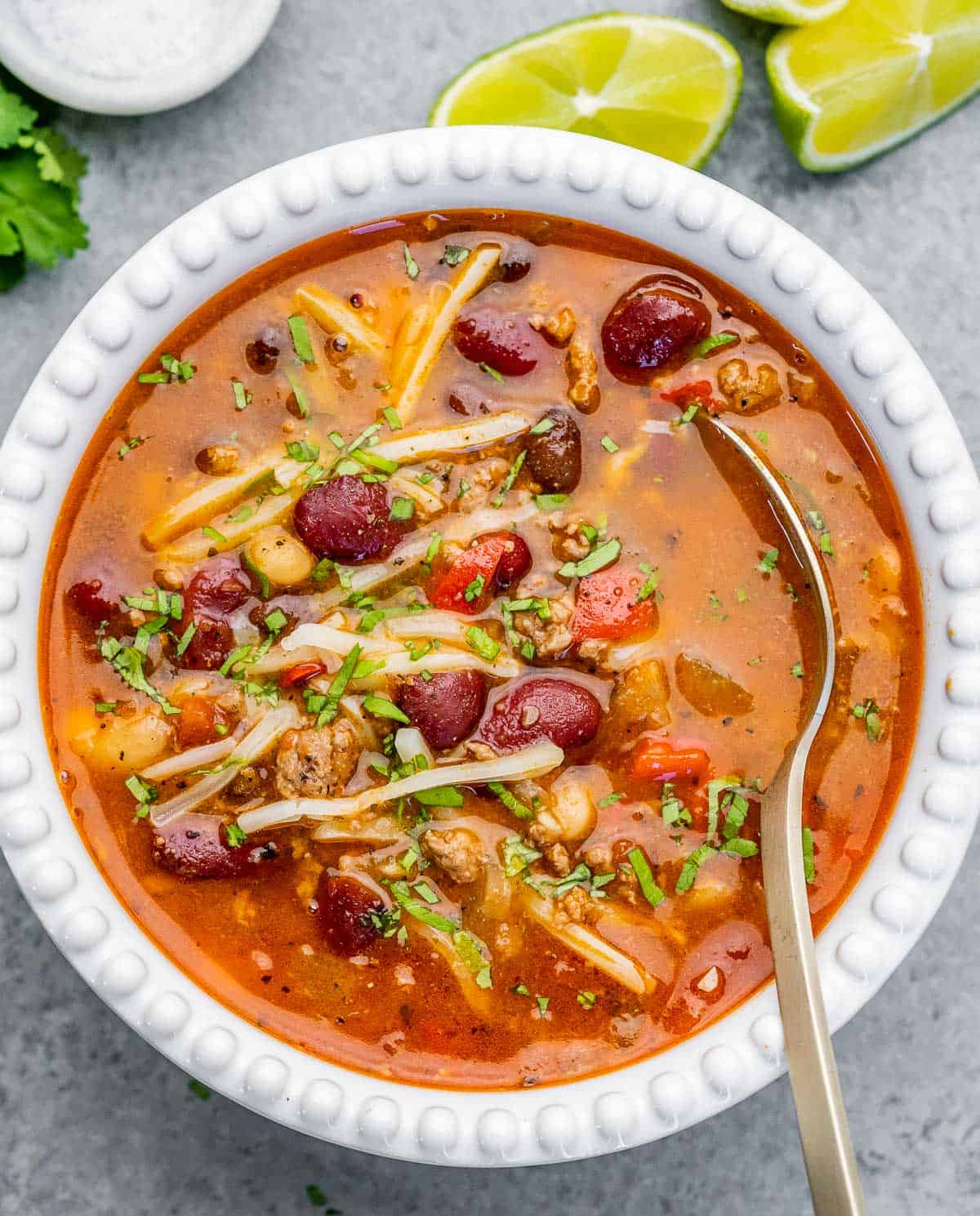 A white bowl of chili with spoon in the bowl.