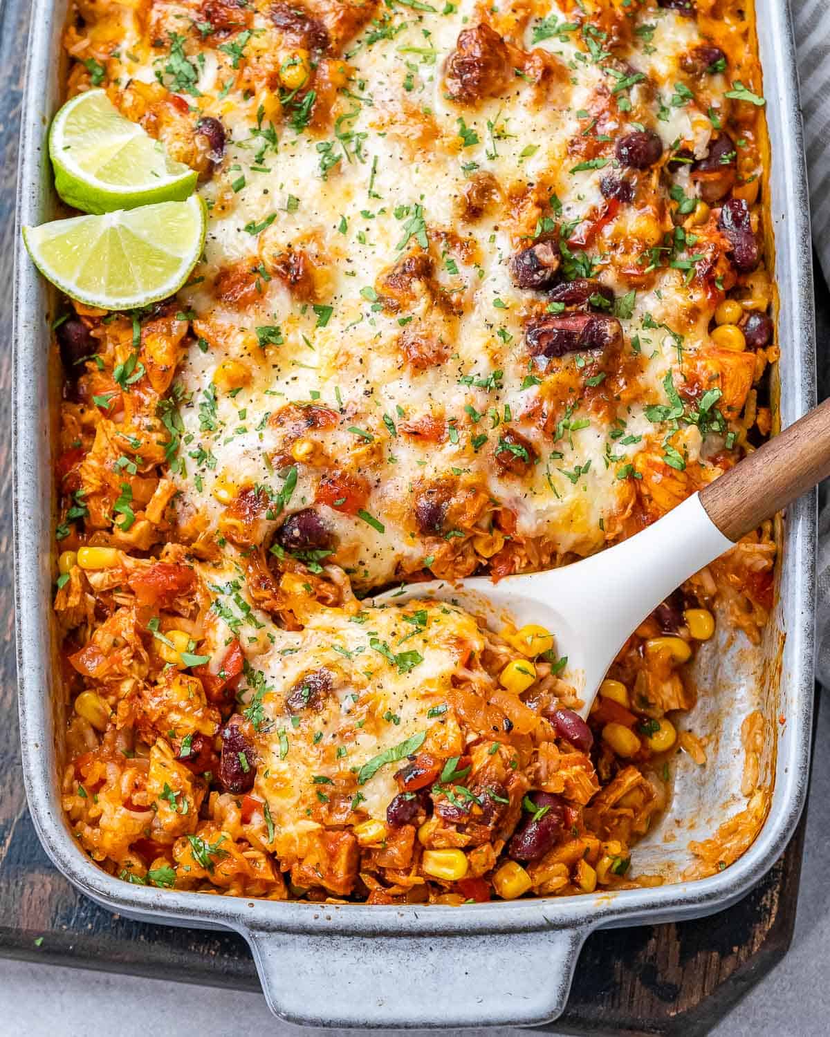 Mexican chicken casserole in baking dish with wooden spoon