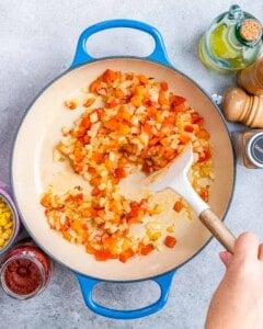 sautéing vegetables in pan with wooden spoon