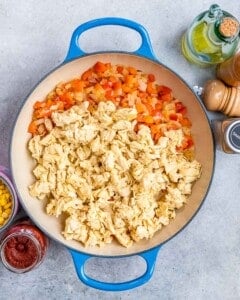 adding chicken to cooked vegetables in pan