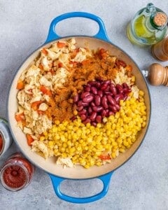 adding tomatoes to cooked chicken and vegetables in pan
